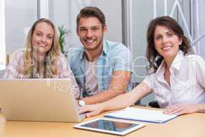 Smiling colleagues with laptop and digital tablet in meeting