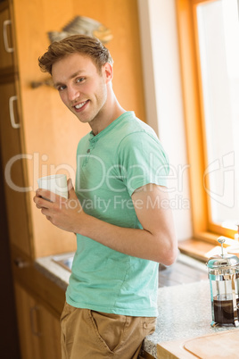 Young man smiling at camera holding coffee