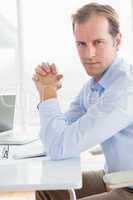 Serious businessman looking at camera at desk