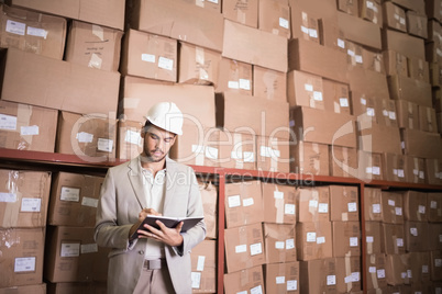 Manager with diary against boxes in warehouse