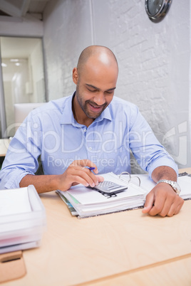 Businessman using calculator at office desk