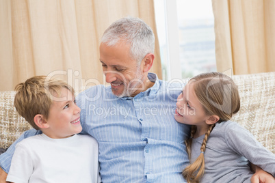 Father smiling with his children on sofa