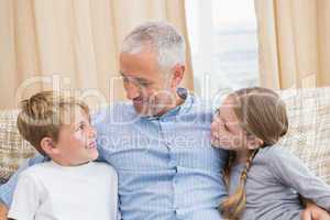 Father smiling with his children on sofa