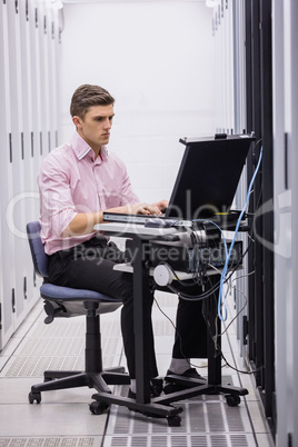 Technician sitting on swivel chair using laptop to diagnose serv