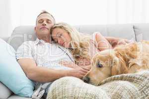 Loving couple napping on couch with their dog
