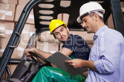 Warehouse manager talking with forklift driver