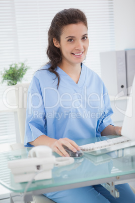 Smiling doctor using mouse of computer