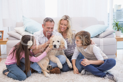 Smiling family with their pet yellow labrador on the rug