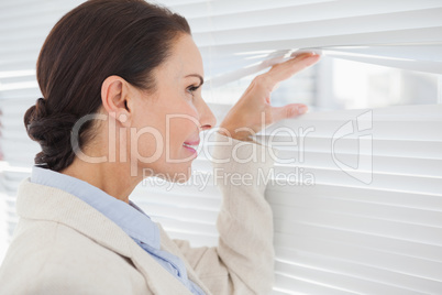 Businesswoman looking through some blinds