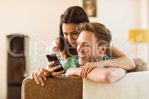 Cute couple looking at smartphone on couch
