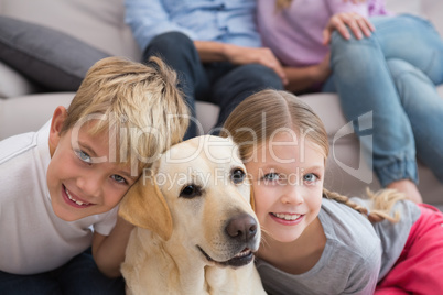 Parents watching children on rug with labrador