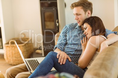 Happy young couple relaxing on the couch with laptop