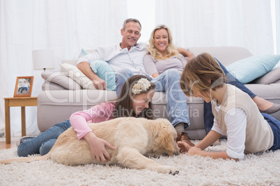Cute siblings playing with dog with their parent on the sofa