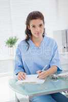 Brunette doctor writing on clipboard