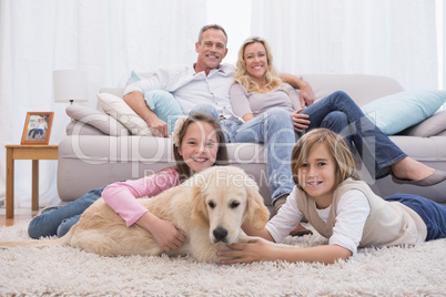 Cute siblings playing with dog with their parent on the sofa