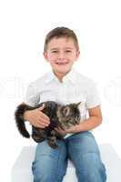 Smiling boy sitting cuddling a grey kitten