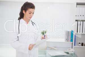 Doctor standing and writing on clipboard