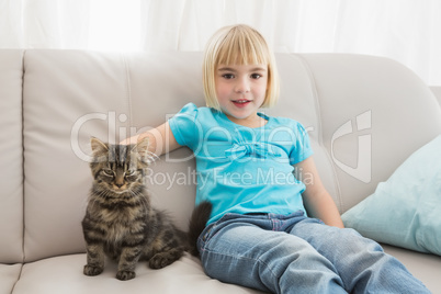 Little girl sitting on the couch stroking her cat