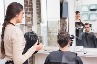 Pretty hair stylist showing man new haircut