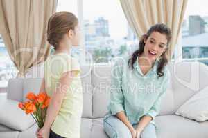 Cute girl hiding flowers from mother