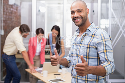 Happy businessman smiling at camera giving thumbs up