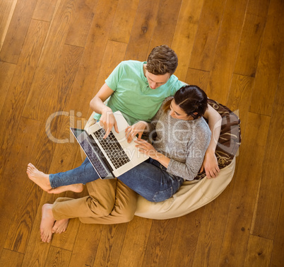 Cute couple using laptop on beanbag