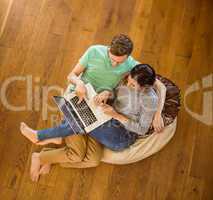 Cute couple using laptop on beanbag