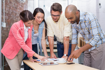 Businesswoman pointing something on tablet to his colleagues