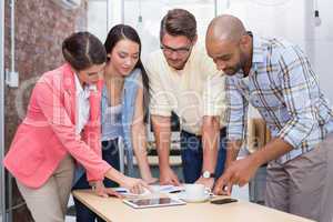 Businesswoman pointing something on tablet to his colleagues