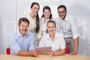 Smiling business people using digital tablet in meeting