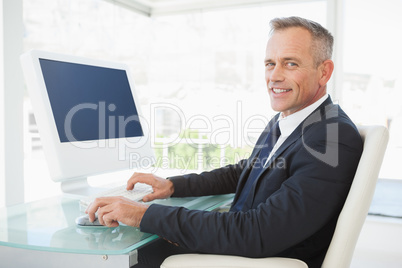 A smiling businessman uses his computer