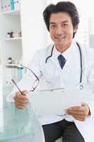 Happy doctor sitting at his desk