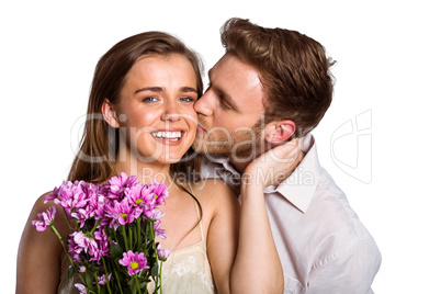 Man kissing woman as she holds flowers