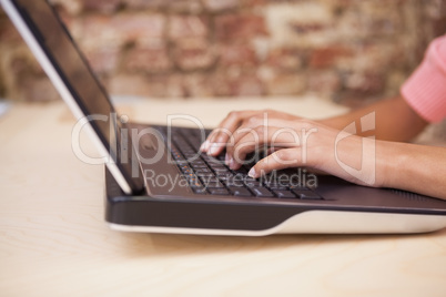 Girl typing on a laptop sitting at her desk