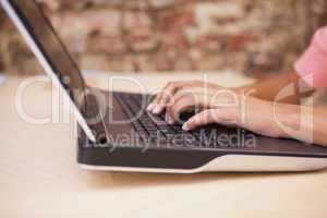 Girl typing on a laptop sitting at her desk