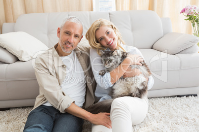 Happy couple with pet cat on floor