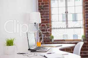 Laptop on desk with glasses and notepad