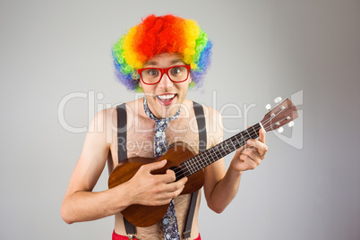 Geeky hipster in afro rainbow wig playing guitar