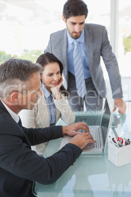 Businessman showing colleagues computer charts Businessman showing colleagues computer charts