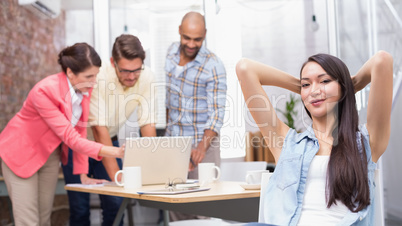 Woman with hands behind head while his colleague working