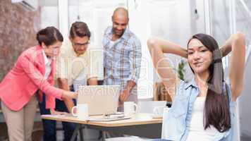 Woman with hands behind head while his colleague working