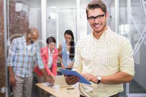 Smiling businessman holding tablet in front of his colleague