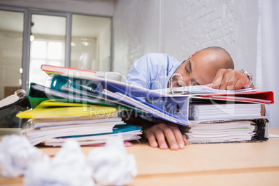 Tired businessman with stack of files on desk