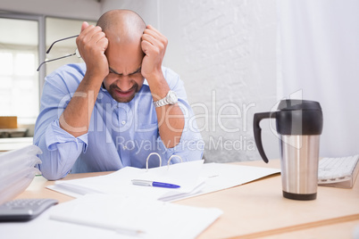 Tired businessman with paperwork at desk