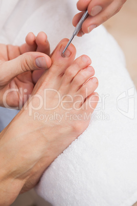 Pedicurist cleaning a customers toe nails