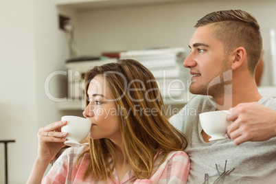 Cute couple relaxing on couch with coffee