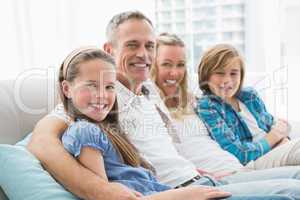 Smiling parents and children sitting together on couch