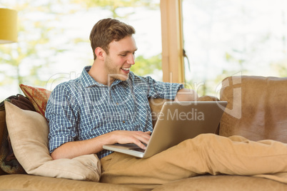 Young man relaxing on his couch with laptop