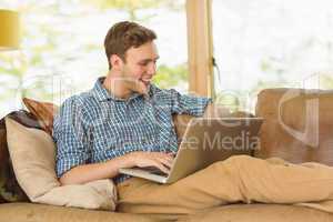 Young man relaxing on his couch with laptop