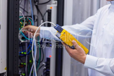 Technician using digital cable analyser on servers